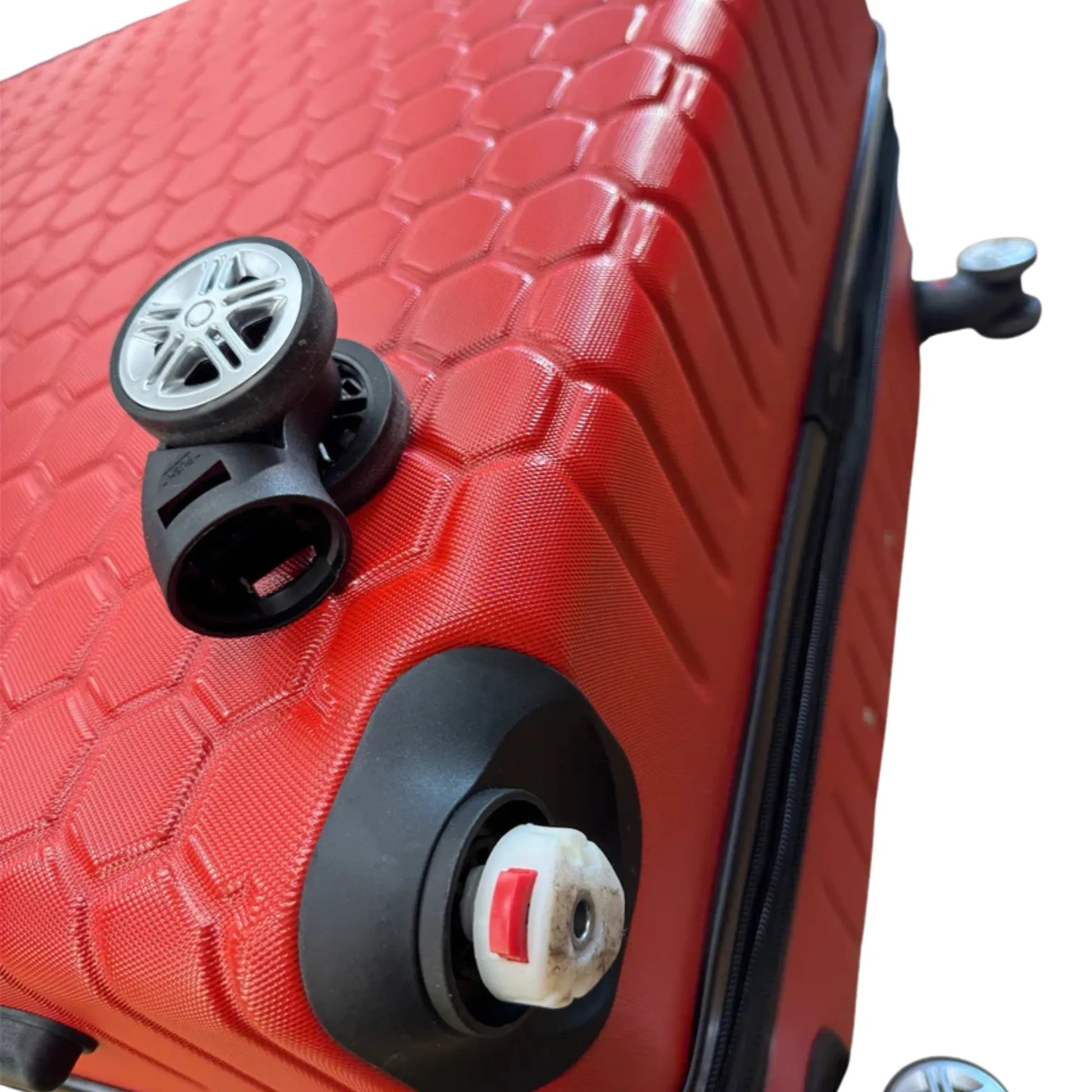 Close-up of a red textured suitcase with wheels and handle on a white background