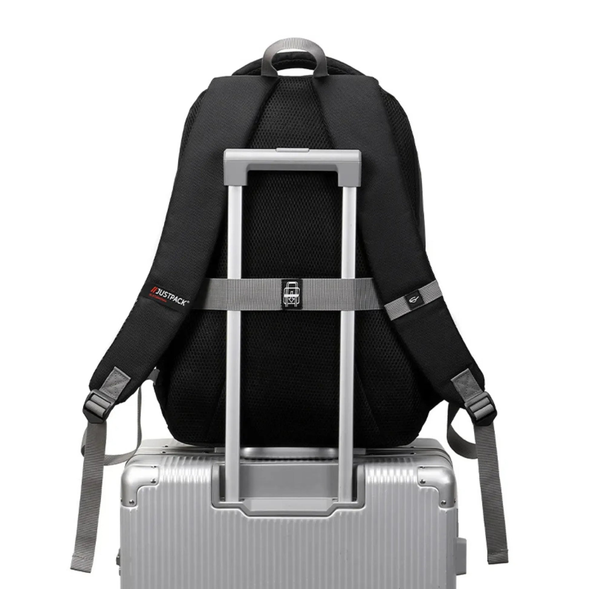 Black backpack with straps on a silver suitcase against a white background